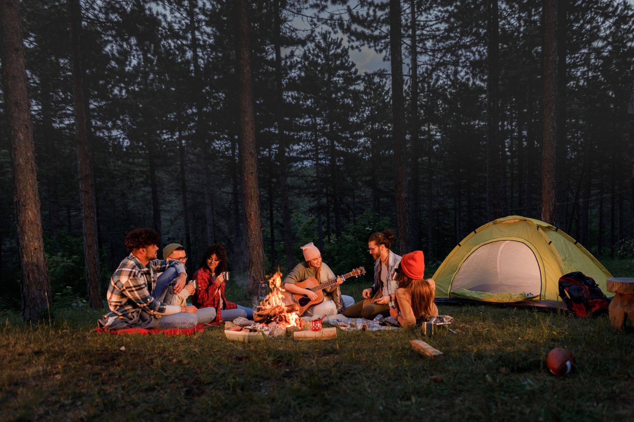 Friends gathered around a campfire at night