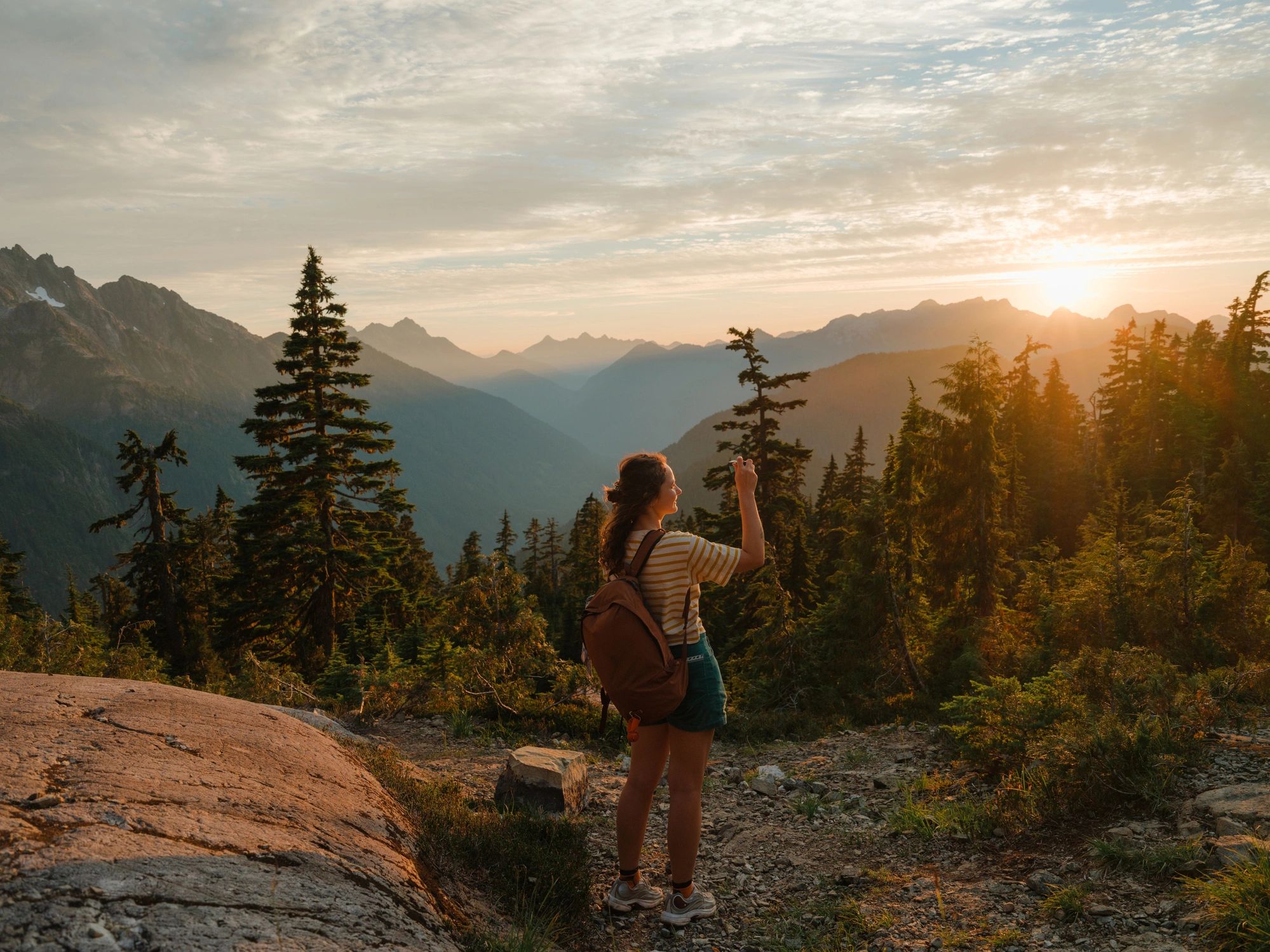 Hiker overlooking a forested mountain landscape